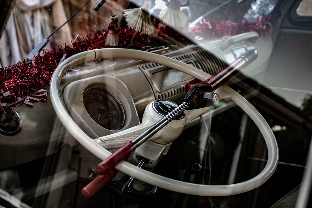 Red and chrome steering wheel lock fitted to a vehicle steering wheel as a visible deterrent against car theft